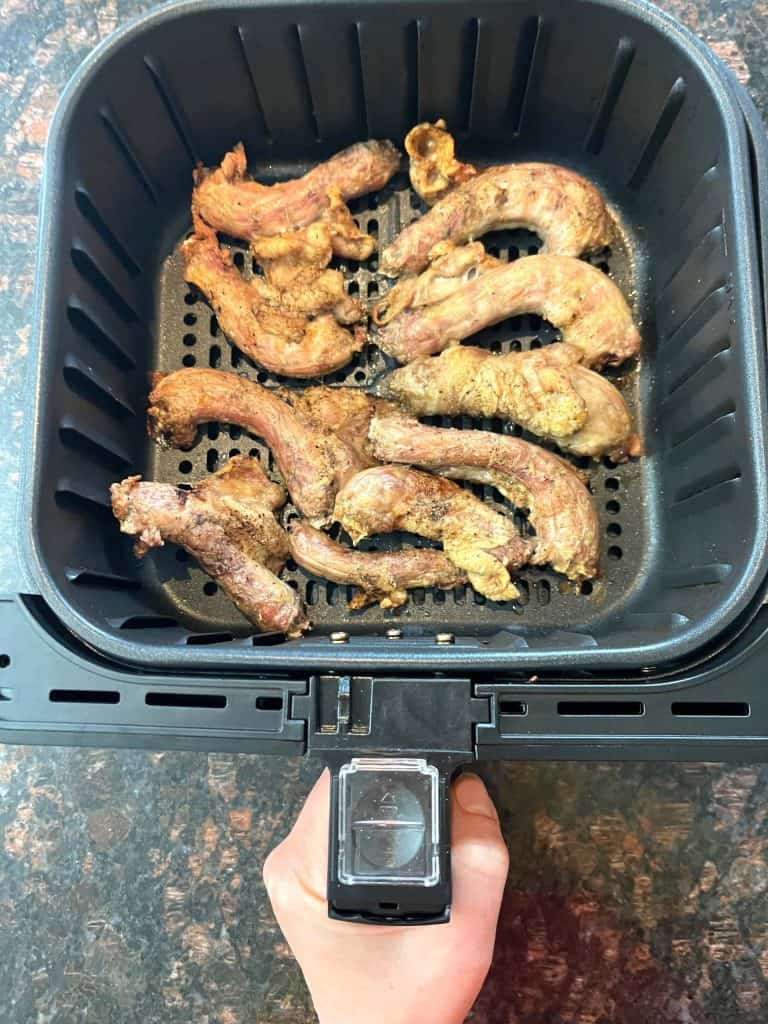 Cooked chicken necks in an air fryer basket after 20 minutes at 400°F, showing their crispy golden-brown finish from the easy Air Fryer Chicken Necks recipe.