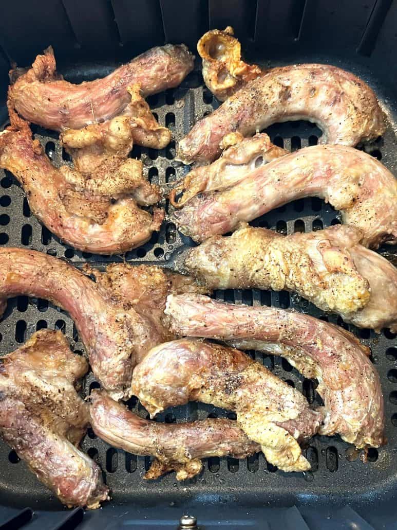 Close-up view of golden brown chicken necks in the air fryer basket, perfectly cooked using the Air Fryer Chicken Necks method.