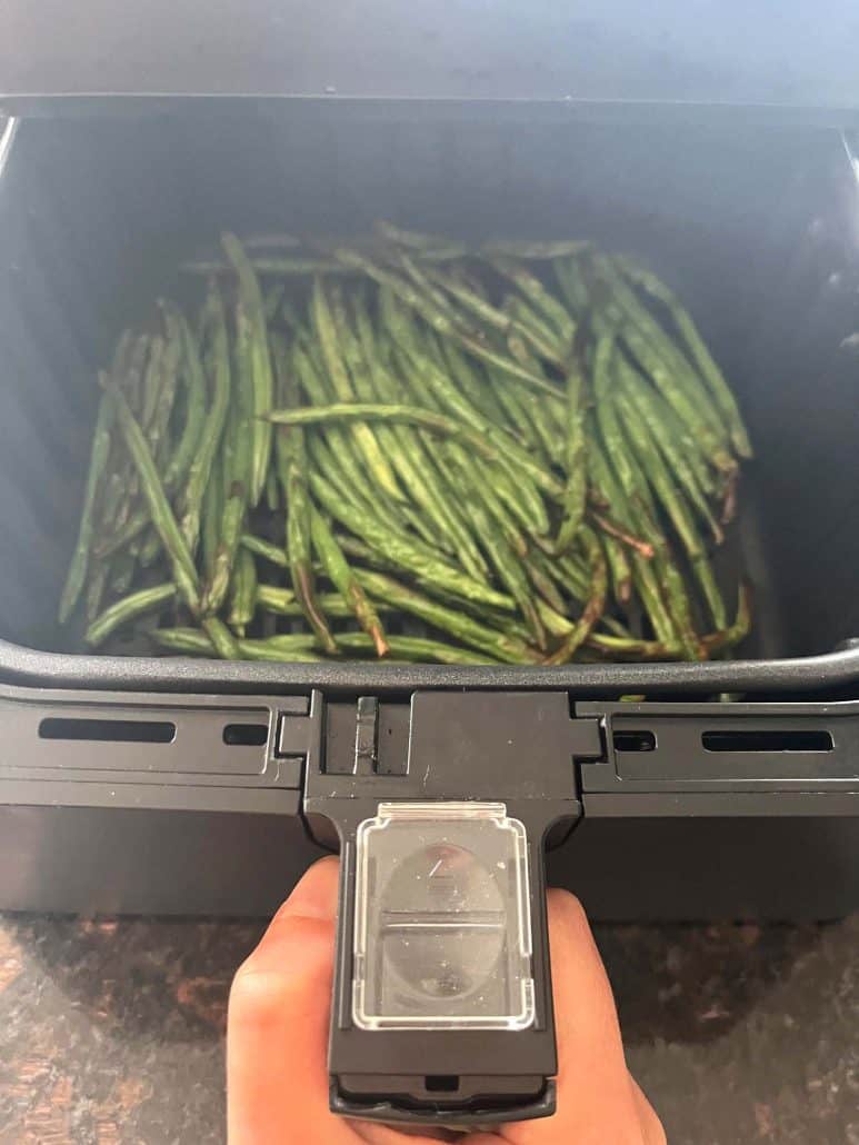 Cooked French green beans (Haricot Verts) in the air fryer basket, perfectly roasted and ready to serve.