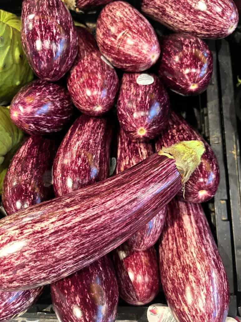 Pile of fresh graffiti eggplants with vibrant purple and white streaks, the star ingredient featured in the Air Fryer Graffiti Eggplant recipe.