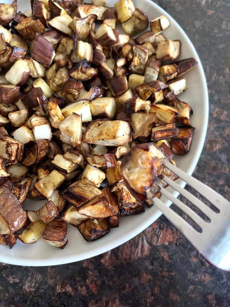 Fork resting on a plate of air-fried graffiti eggplant, highlighting the crispy golden edges.