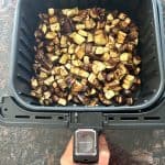 Freshly cooked graffiti eggplant cubes in an air fryer basket, perfectly browned and ready to serve.