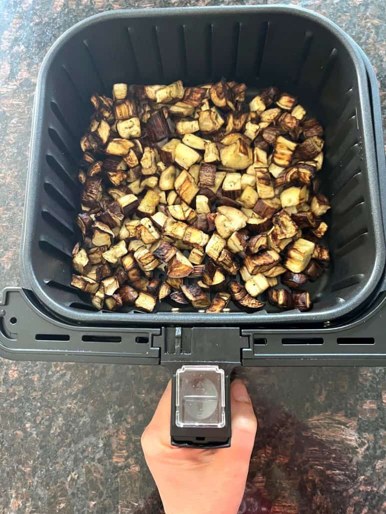 Freshly cooked graffiti eggplant cubes in an air fryer basket, perfectly browned and ready to serve.
