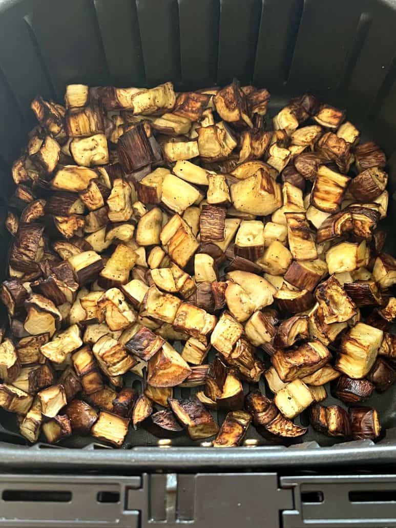 Top view of perfectly golden and crispy graffiti eggplant pieces inside the air fryer basket.