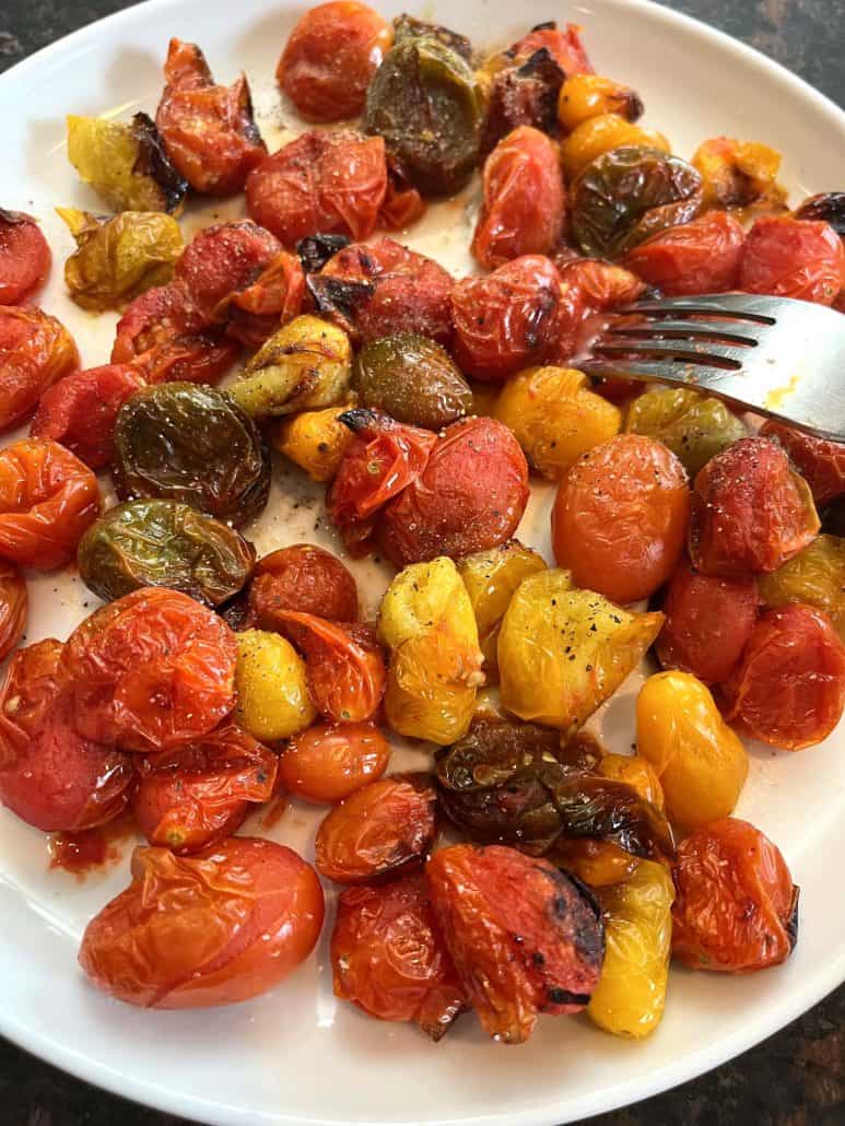 Air fried medley tomatoes served on a plate with a fork, ready to eat as shown in the Air Fryer Medley Tomatoes recipe.