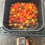 Freshly roasted medley tomatoes in an air fryer basket, perfectly blistered and ready to season.