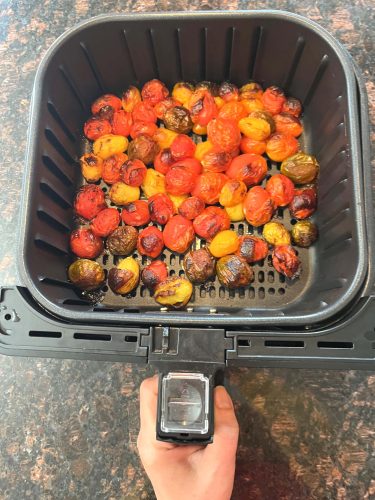 Freshly roasted medley tomatoes in an air fryer basket, perfectly blistered and ready to season.