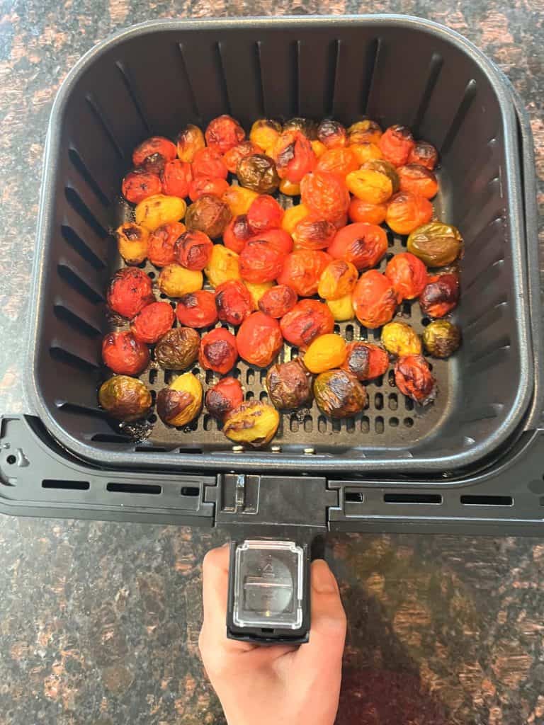 Freshly roasted medley tomatoes in an air fryer basket, perfectly blistered and ready to season.