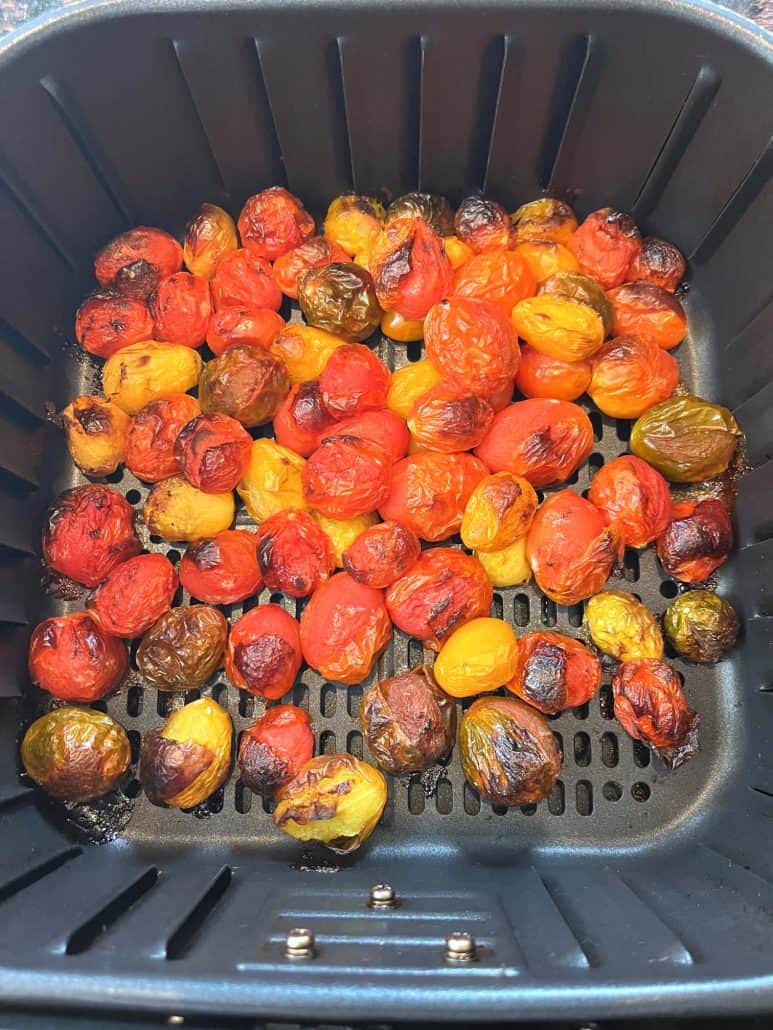 Top view of roasted medley tomatoes in the air fryer basket, showcasing the vibrant colors and blistered skins.