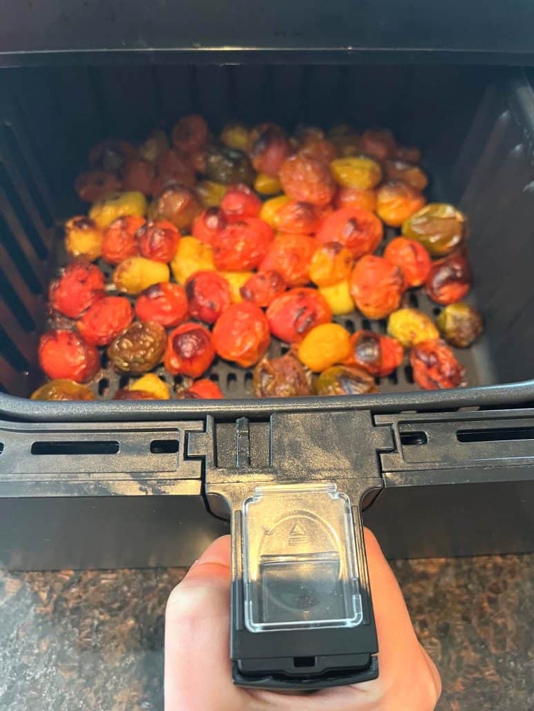 Freshly air fried medley tomatoes in the basket, lightly browned and blistered, just finished cooking.
