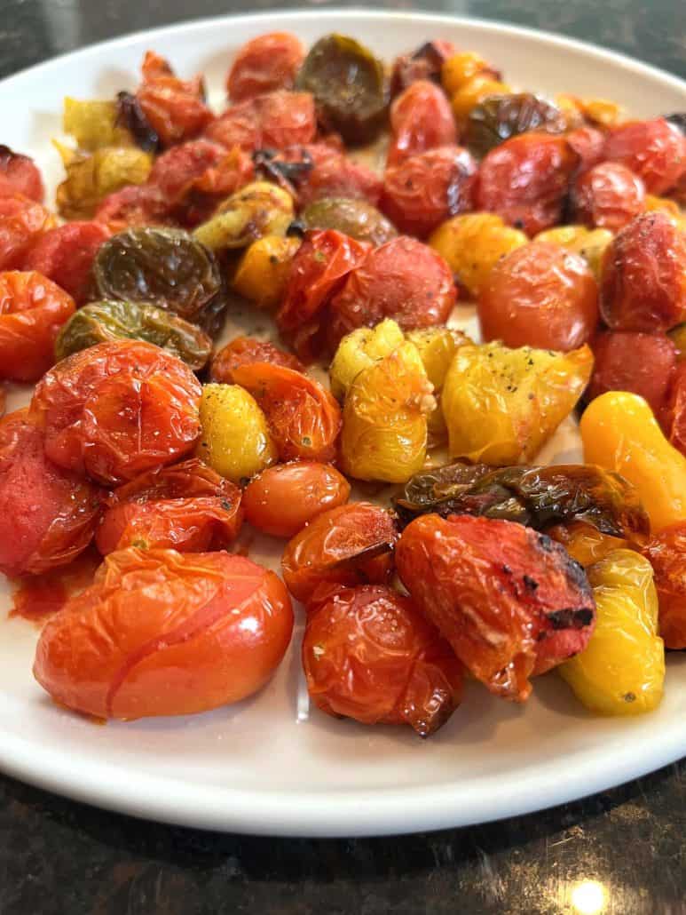 Juicy, roasted medley tomatoes on a white plate, showcasing their vibrant colors and blistered texture from the Air Fryer Medley Tomatoes recipe.