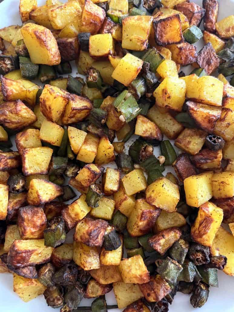 Top view of a plate full of air fryer okra and potatoes, showing a colorful mix of golden brown, crispy vegetables fresh and ready to eat.