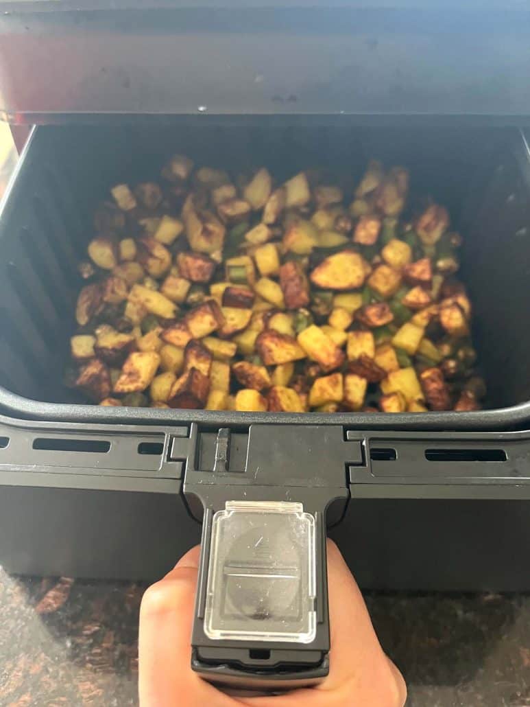 Golden brown okra and potatoes cooked in the air fryer, shown after shaking the basket halfway through for even crisping.