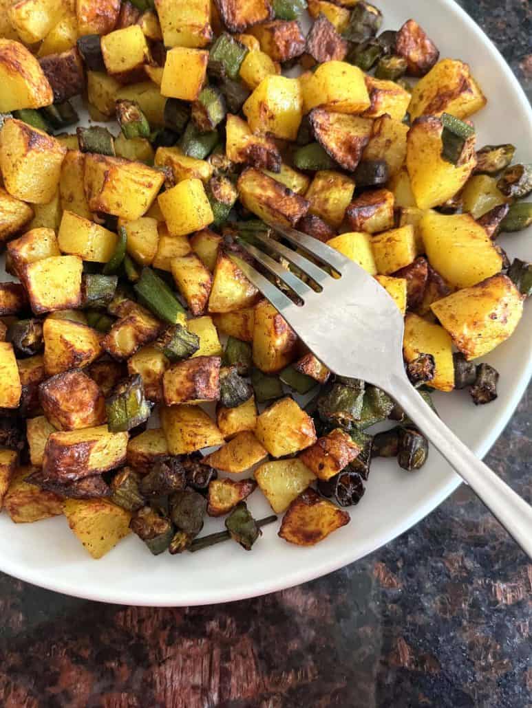 Plate of crispy air fryer okra and potatoes with a fork ready to dig in, highlighting the dish's golden texture.