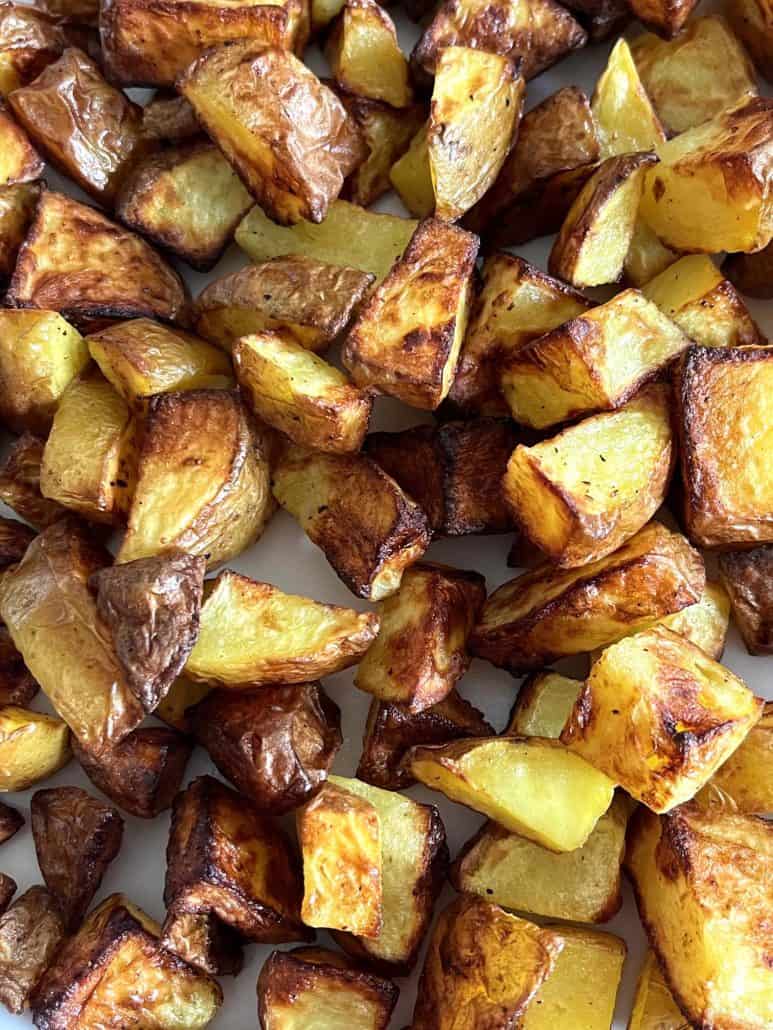 Close-up view of golden brown, crispy air fryer skin-on potato cubes piled on a plate—freshly cooked and ready to serve.