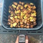 Golden brown skin-on potato cubes freshly cooked in the air fryer basket, perfectly crisped and ready to serve.