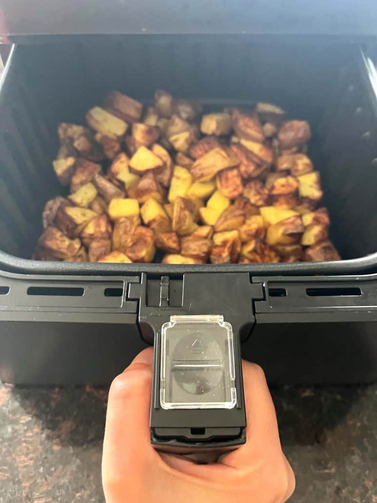 Air fryer basket filled with freshly cooked, golden brown skin-on potato cubes—crispy and ready to enjoy.