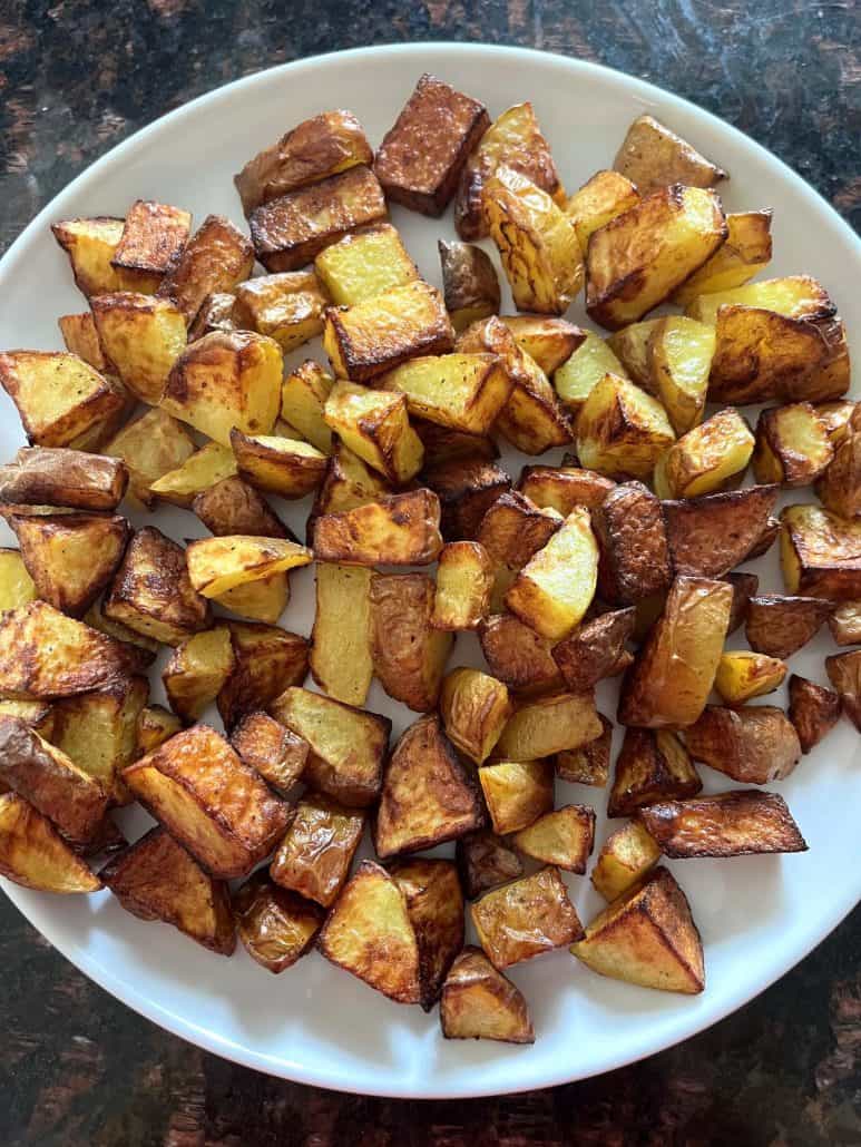Air fryer skin-on potato cubes served on a white plate, perfectly golden and ready to enjoy.