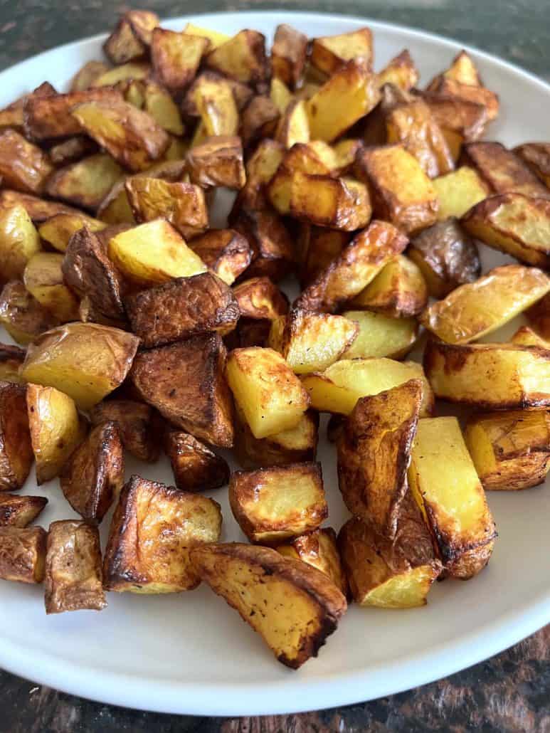Crispy air fryer potato cubes with skin, served hot on a white plate—fresh from the Air Fryer Skin On Potatoes recipe.