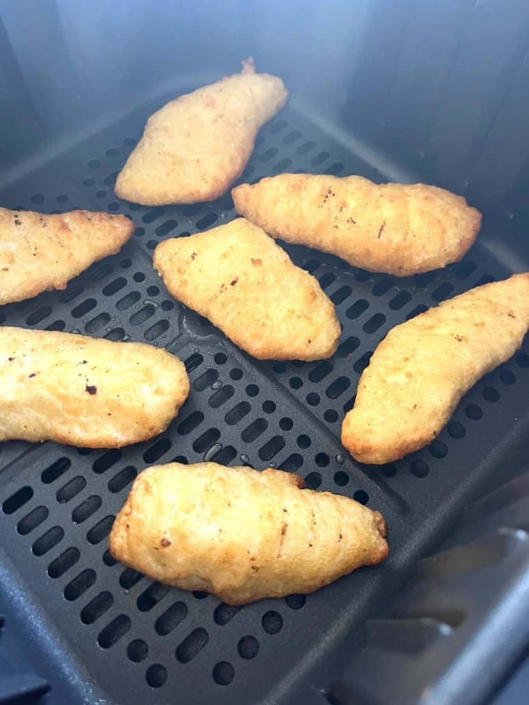 Close-up of crispy golden Trader Joe’s battered halibut fillets inside the air fryer basket after cooking.