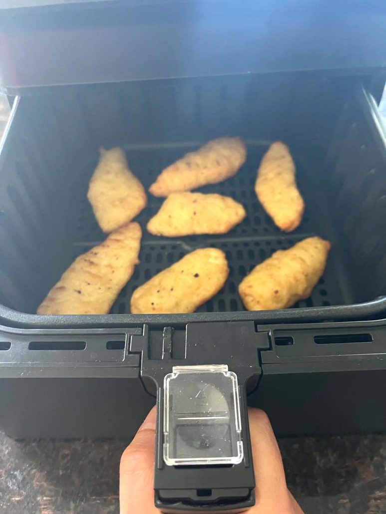 Cooked Trader Joe’s battered halibut fillets inside the air fryer basket, hot and crispy after 10 minutes of air frying.