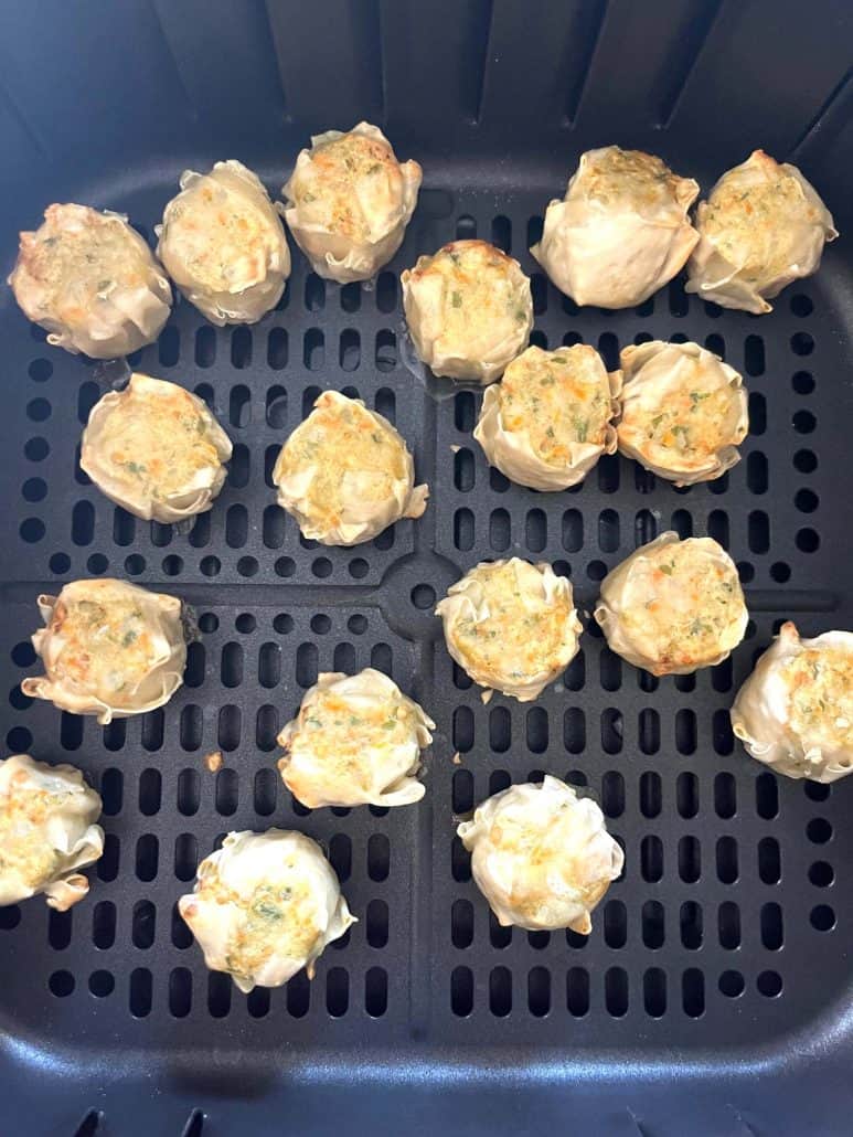 View of golden-brown Trader Joe’s Chicken Shu Mai dumplings in the air fryer basket after cooking with the steam method.