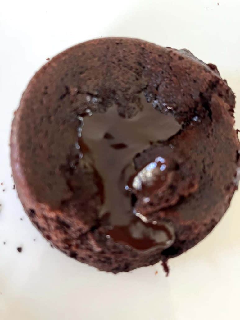 Trader Joe’s chocolate lava cake on a white plate with melted chocolate center visible, showing the rich, gooey texture.