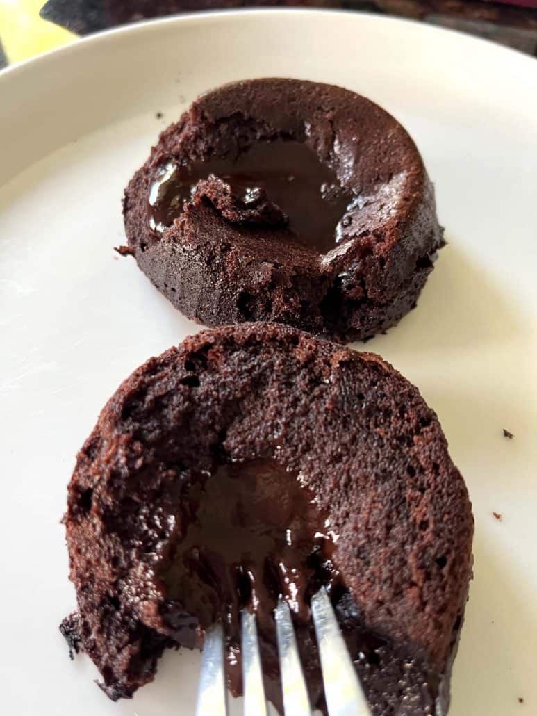 Fork cutting into a Trader Joe’s chocolate lava cake on a plate, showing the rich, gooey chocolate center spilling out.