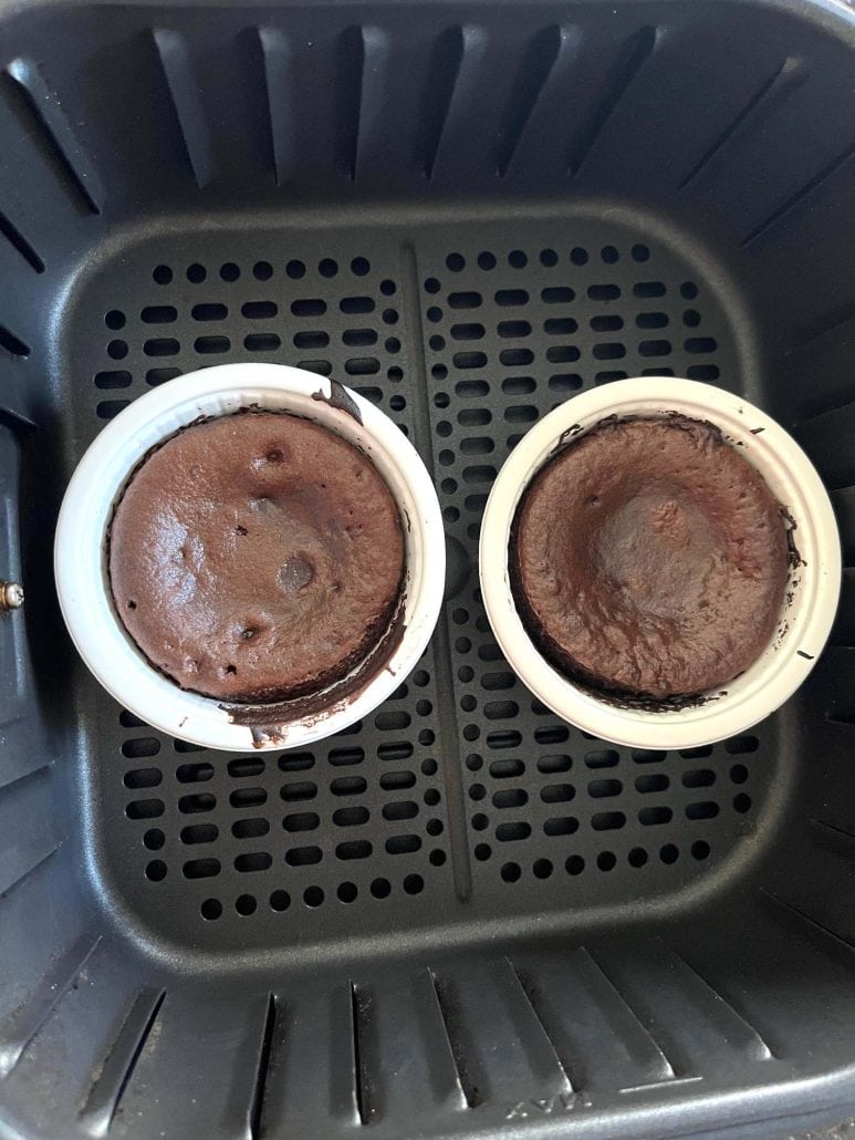 Two fully cooked Trader Joe’s chocolate lava cakes in the air fryer basket, showing the finished result after 6 minutes at 400°F.