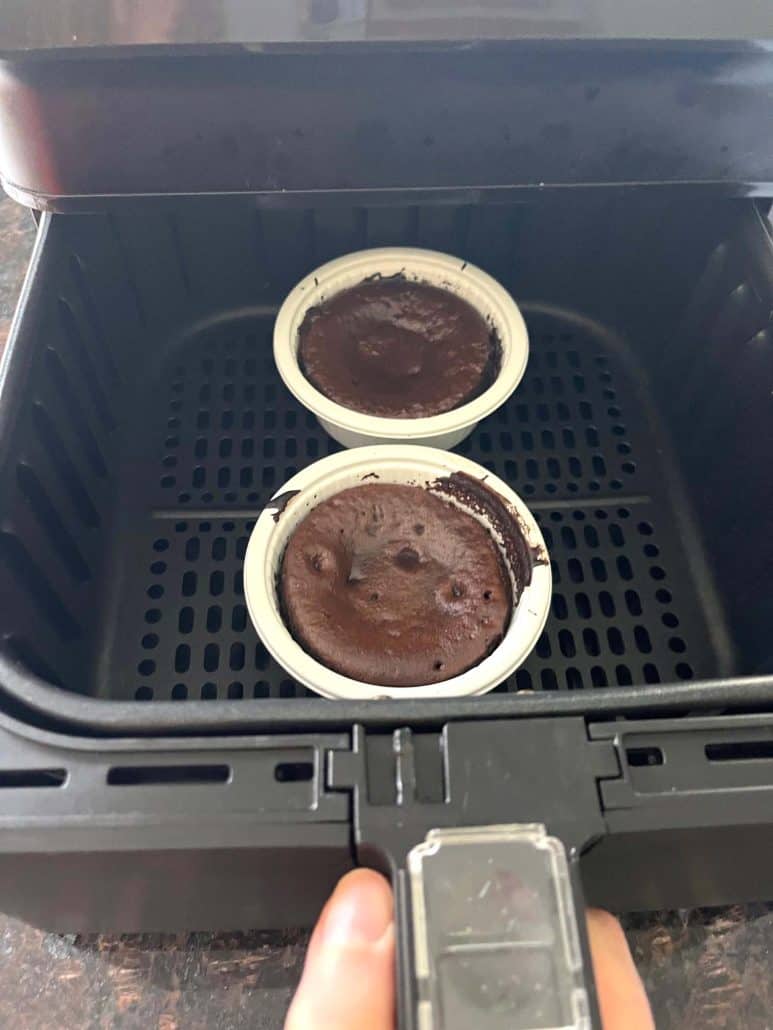 Two frozen Trader Joe’s chocolate lava cakes placed in the air fryer basket before cooking, demonstrating the no-preheat air fryer method.