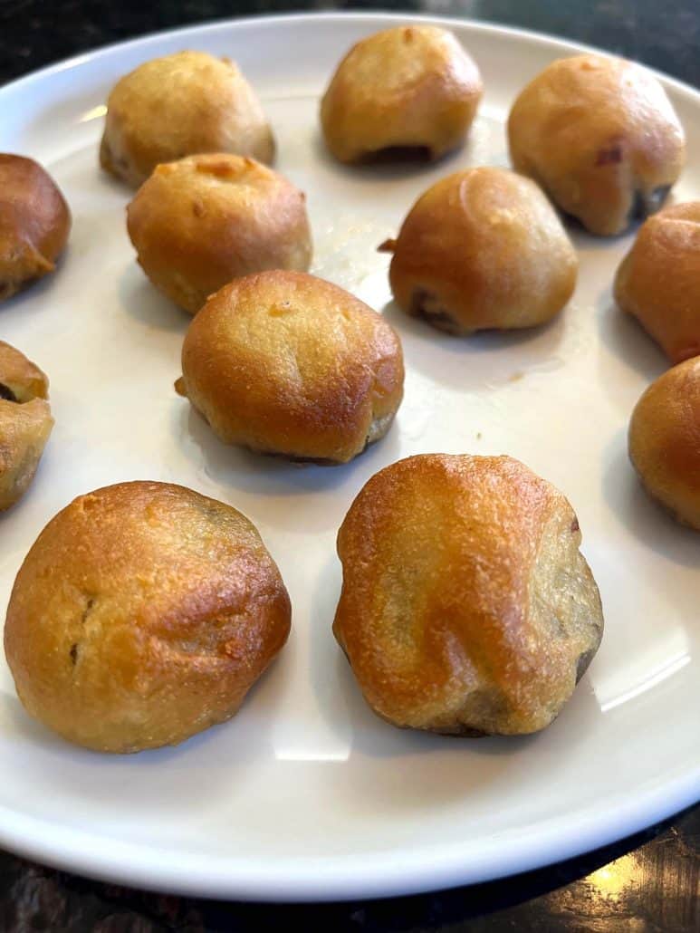 Golden brown air-fried dough balls on a white plate, showcasing their crispy texture and slightly uneven browning.