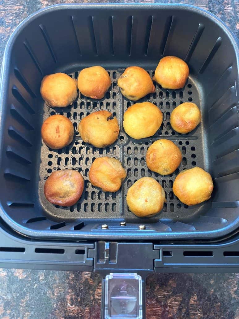 Golden brown air-fried dough balls in an air fryer basket, showing the perfect crispiness and texture for a quick snack or dessert.
