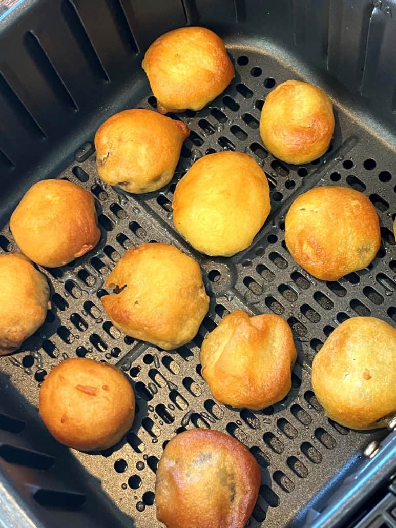 Golden brown, perfectly crisp dough balls in an air fryer basket, ready to be served.