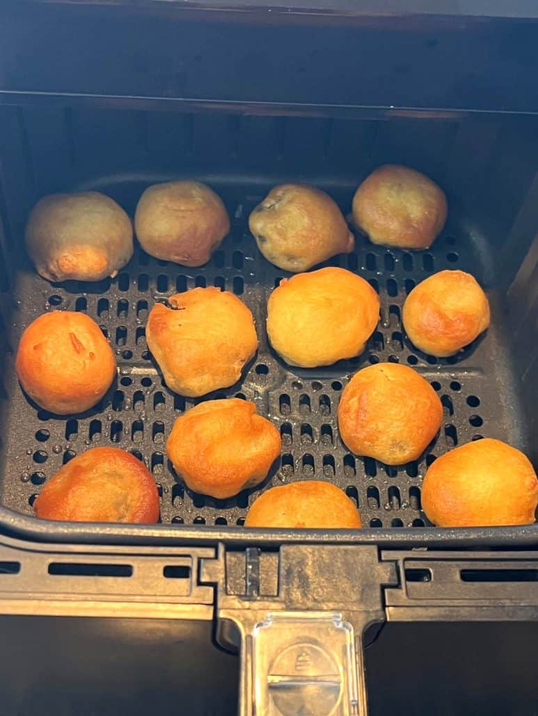 Close-up view of golden brown dough balls in an air fryer basket, perfectly crisped.