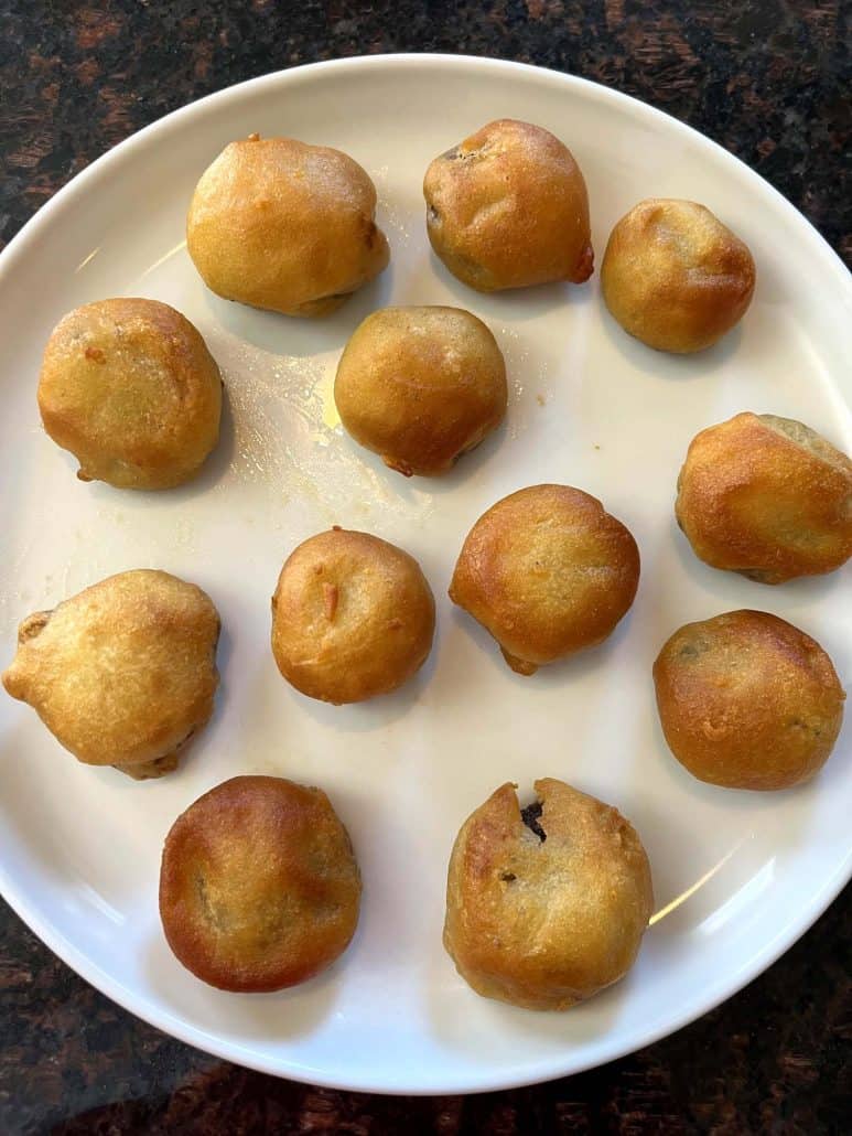 Golden brown air-fried dough balls arranged on a white plate, showing their crispy texture and slightly varied color.