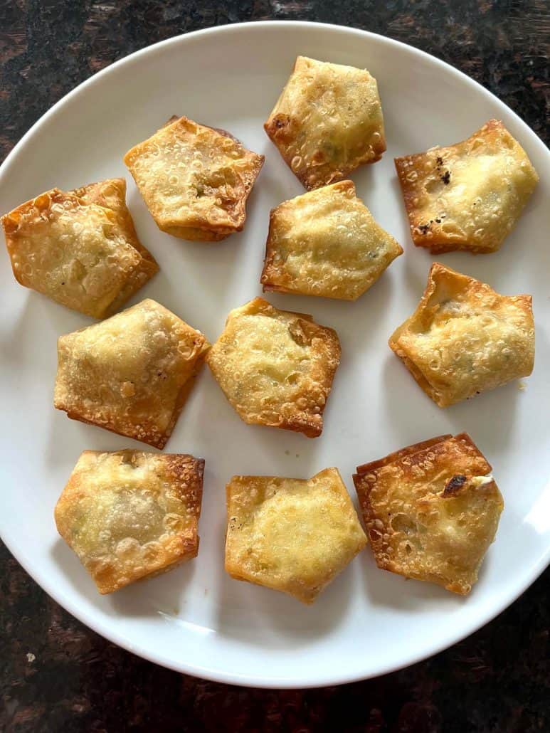 Golden brown Trader Joe’s crispy wontons arranged on a white plate after air frying.
