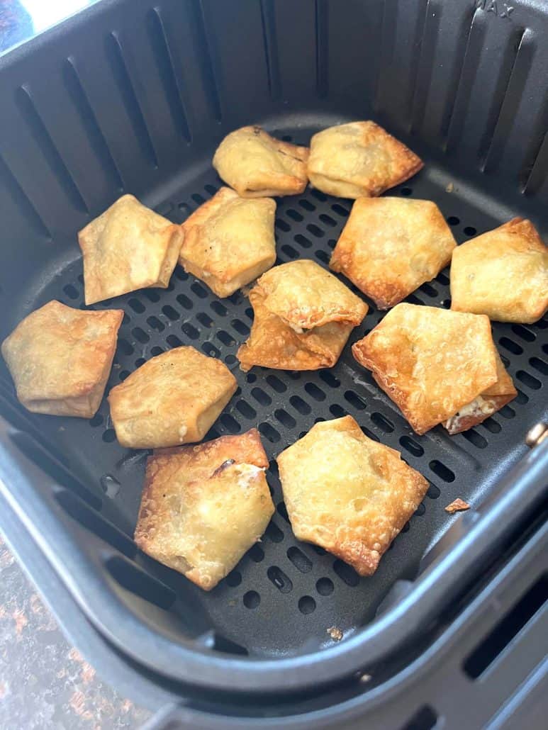 Golden brown jalapeño cream cheese wontons in the air fryer basket, freshly cooked.