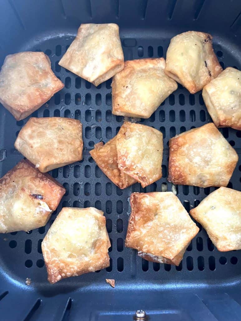 Air fryer basket filled with crispy, golden Trader Joe’s wontons, fresh from cooking and ready to enjoy.