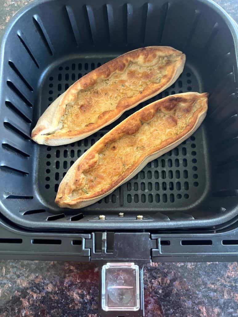 Two golden brown Trader Joe’s Garlic Gondolas cooked in the air fryer basket.
