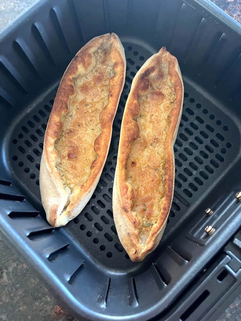Two air-fried Trader Joe’s Garlic Gondolas with a golden, crisped crust sitting in the air fryer basket—perfectly cooked and ready to serve.