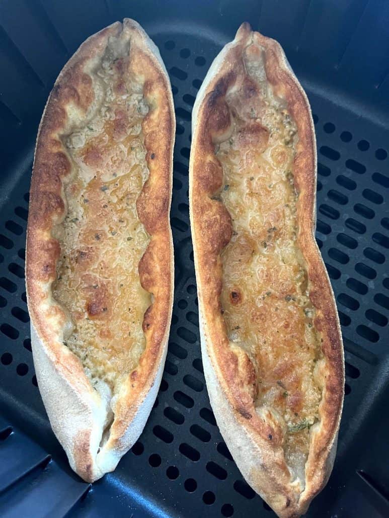 Close-up of two golden brown Trader Joe’s Garlic Gondolas in the air fryer basket, showing the perfectly crisped crust.
