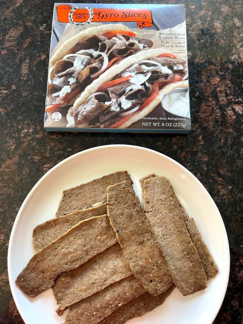 Cooked Trader Joe’s gyro slices served on a white plate with the product box displayed in the background.