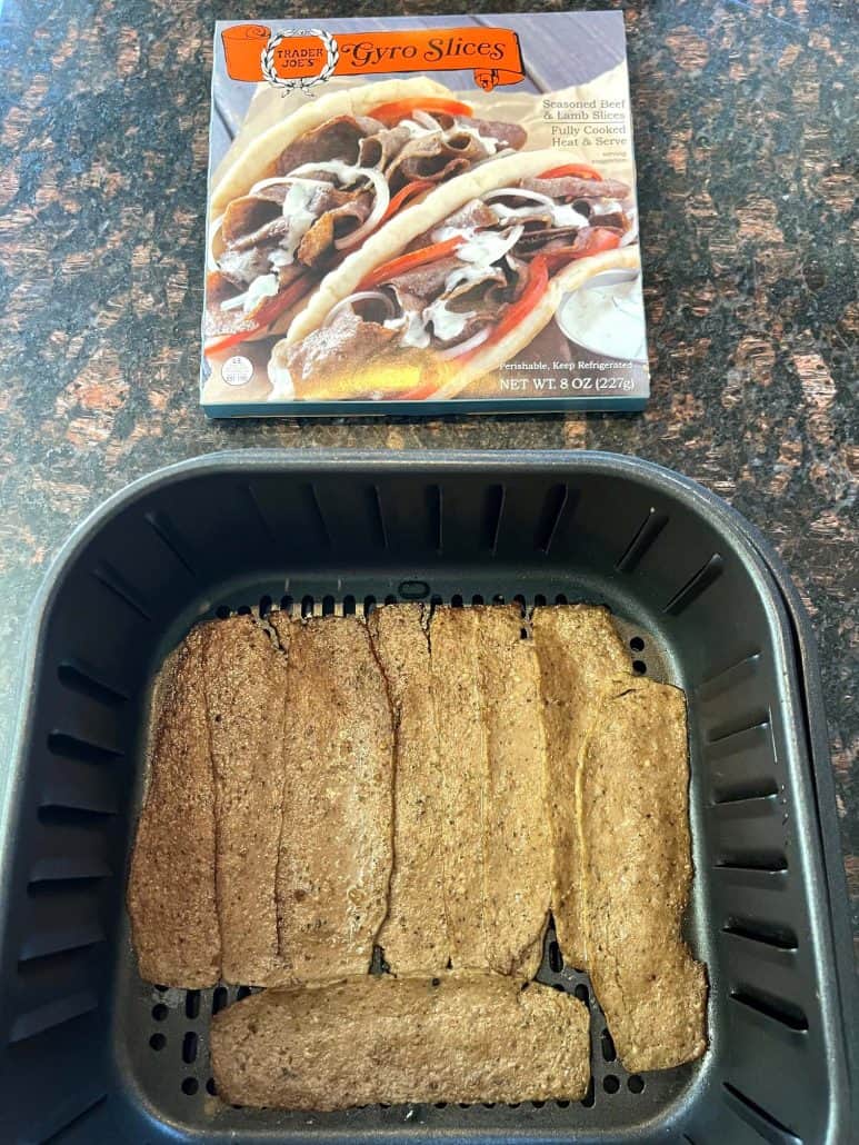 Trader Joe’s gyro slices arranged in an air fryer basket with the product box in the background, ready to cook