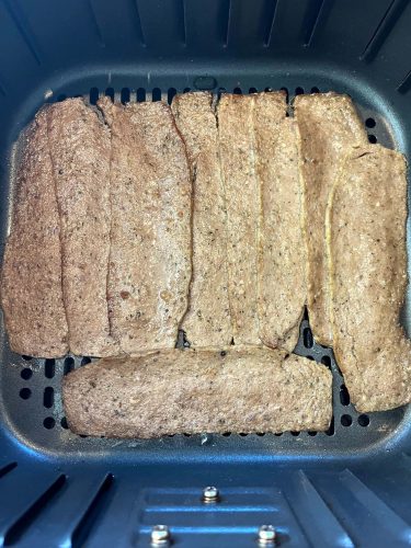Close-up of Trader Joe’s gyro slices arranged in an air fryer basket before cooking.