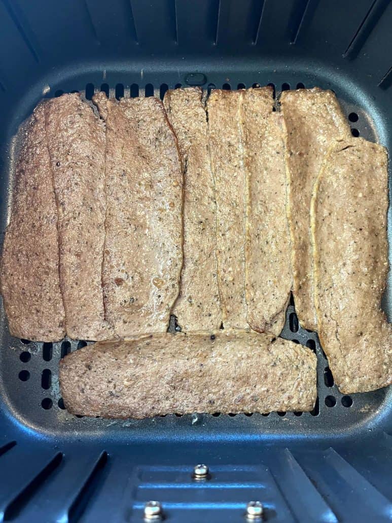 Close-up of Trader Joe’s gyro slices arranged in an air fryer basket before cooking.