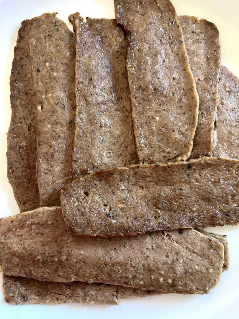 Close-up of cooked Trader Joe’s gyro slices on a white plate after air frying, ready to serve.