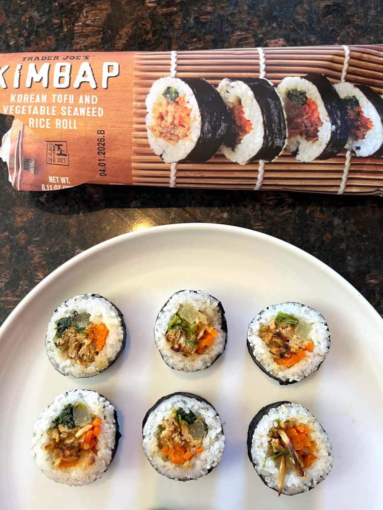 Close-up of cooked Trader Joe's kimbap rolls on a plate with the package displayed in the background.