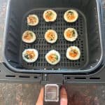Frozen Trader Joe's kimbap arranged in a single layer inside an air fryer basket before cooking.