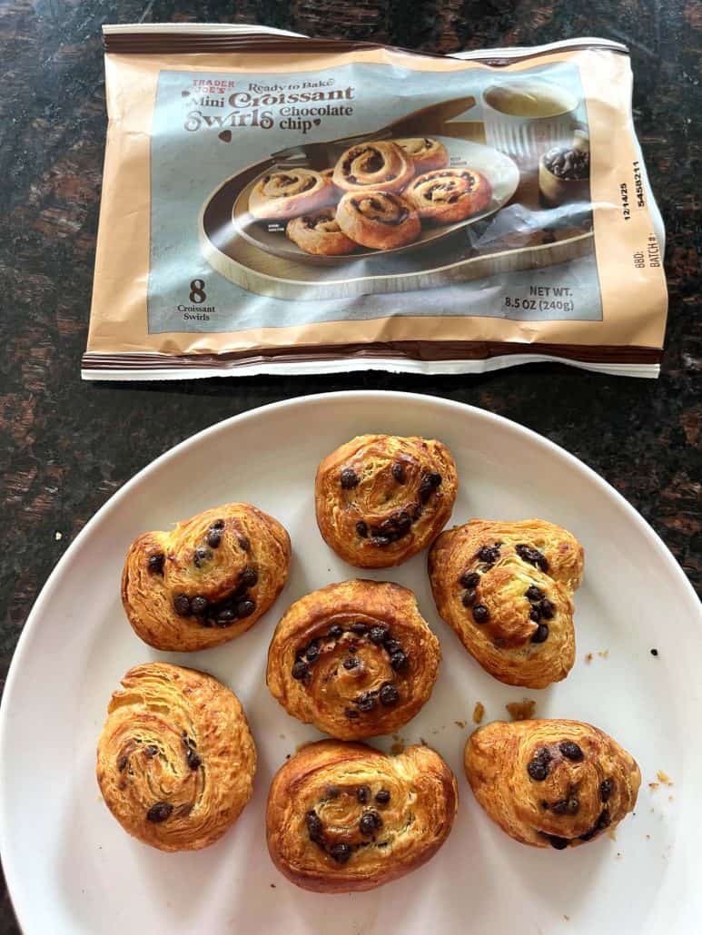 Plate of freshly baked Trader Joe’s Mini Croissants, golden and flaky, with the product package displayed beside them.