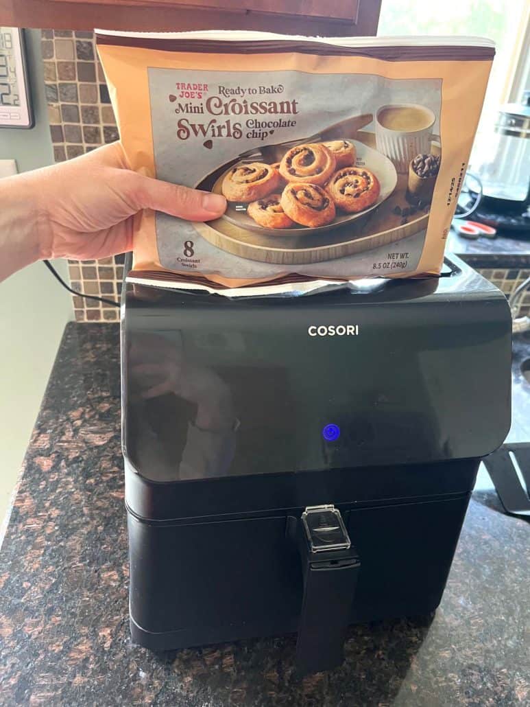 Hand holding a package of Trader Joe’s Mini Croissants, about to be placed in the air fryer for cooking.